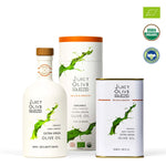 Juicy Olive Soluzzid organic extra virgin olive oil set including a 500ml white bottle with a cork stopper, a matching white cylindrical box with an orange lid, and a 12 fl oz can, shown alongside USDA Organic and Bio certification badges on a white background.